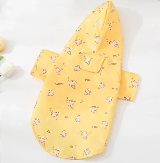 Small dog wearing a bright yellow short-sleeve summer raincoat outdoors.

